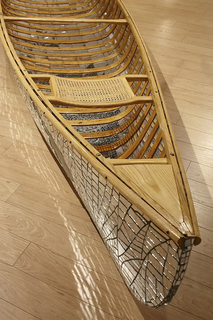 A canoe with mirror fragments lying face up on the gallery floor.