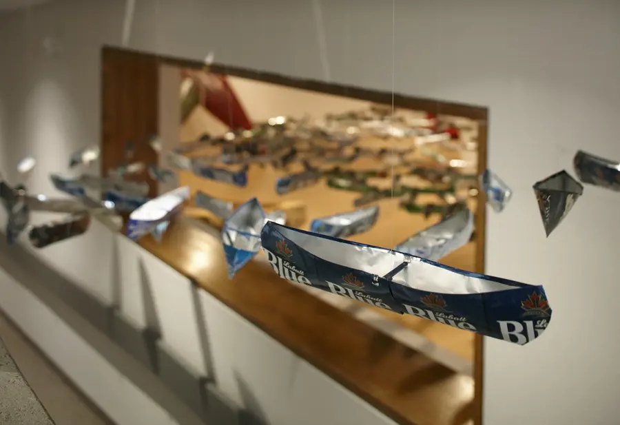 A series of miniature canoe sculptures with beer branding are hanging from the ceiling.