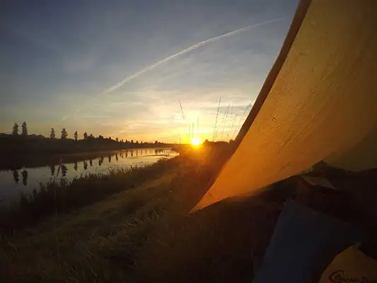 Close up of a tent overlooking a river at sunset.