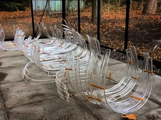 Unassembled glass sculpture pieces inside a grass greenhouse.